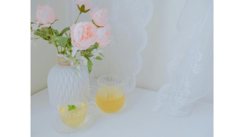 花瓶にバラとグラスに飲み物が置かれた写真