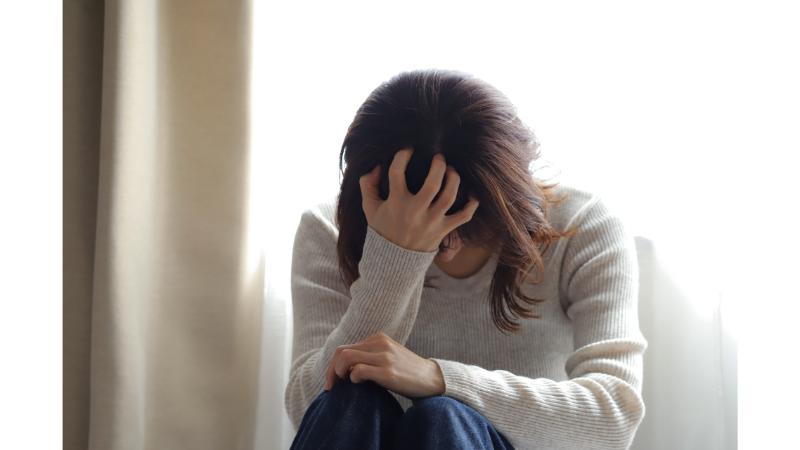 片手で頭を押さえうつむく女性