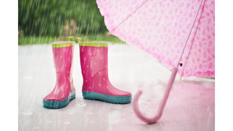 雨に打たれるピンクの傘と長靴