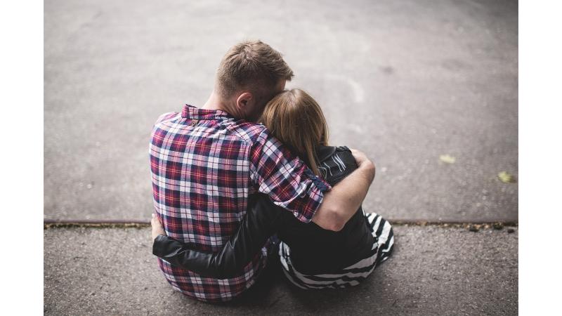 地面に座り肩を抱き合う男女の後ろ姿
