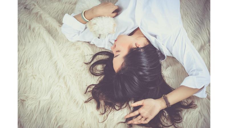子犬を抱きながら仰向けで眠る女性