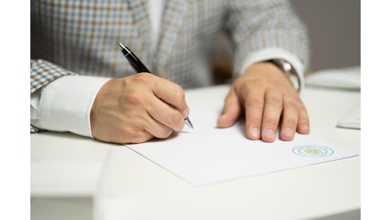 書類にサインをする男性の手元