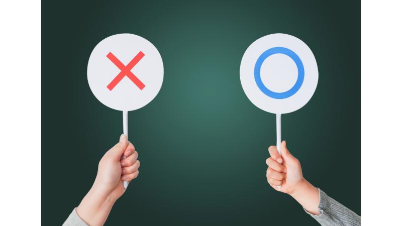 マルとバツの札を持った女性の手元