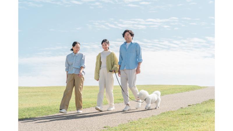 小道を散歩する夫婦と子供と白い犬