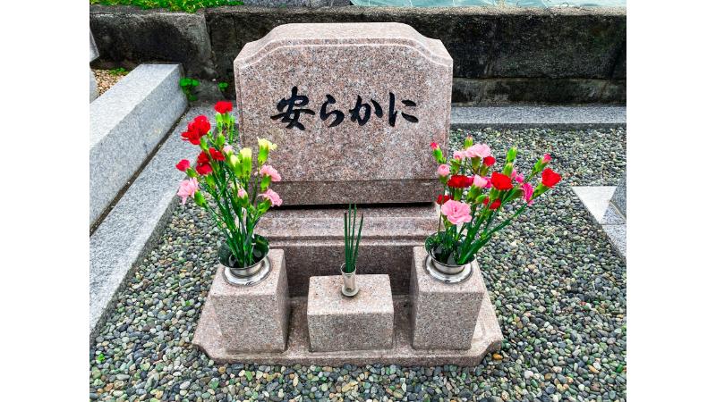 赤やピンクの花が生けられたお墓