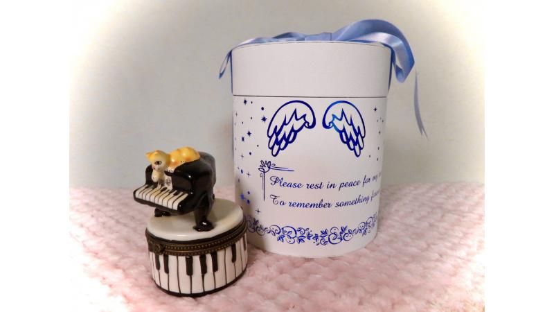 青いリボンが結ばれた骨壺とピアノの置物