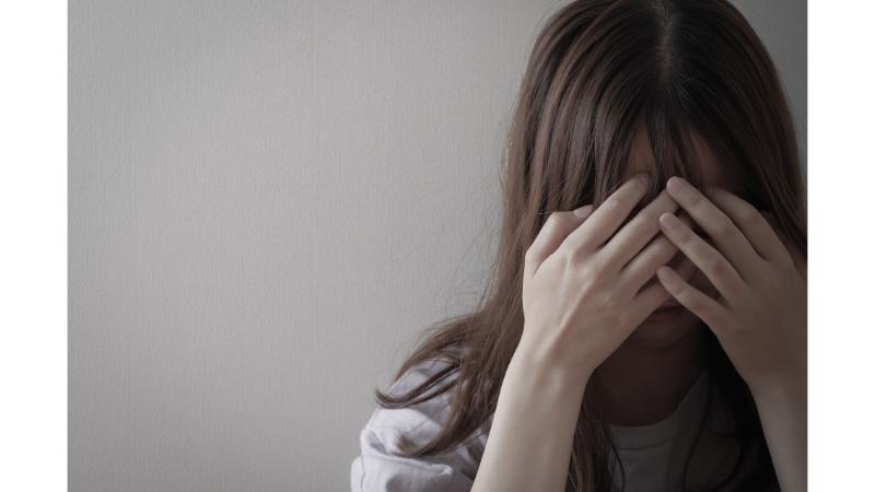 手で顔を覆い悲しむ女性