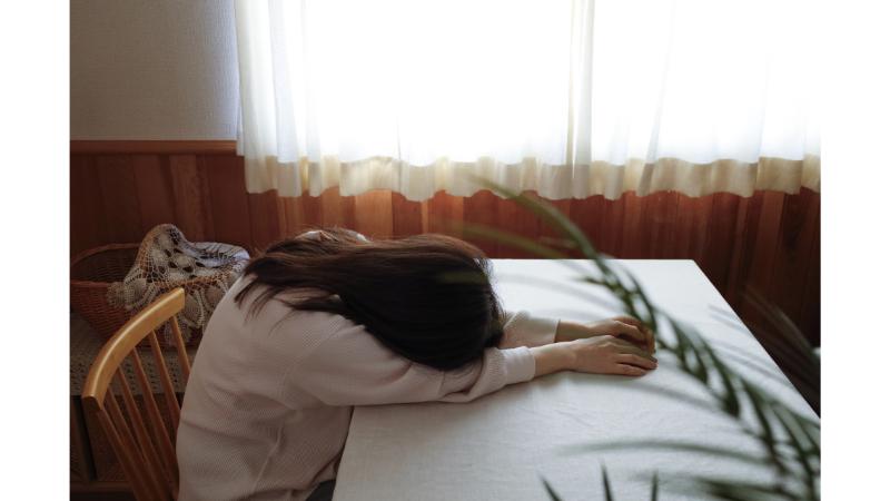 机にうつぶせになる女性