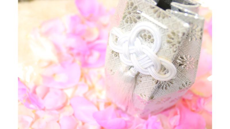 ピンクの花びらの上に置かれた白い骨壺