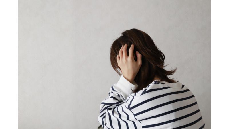 頭を抱え後ろを向く女性