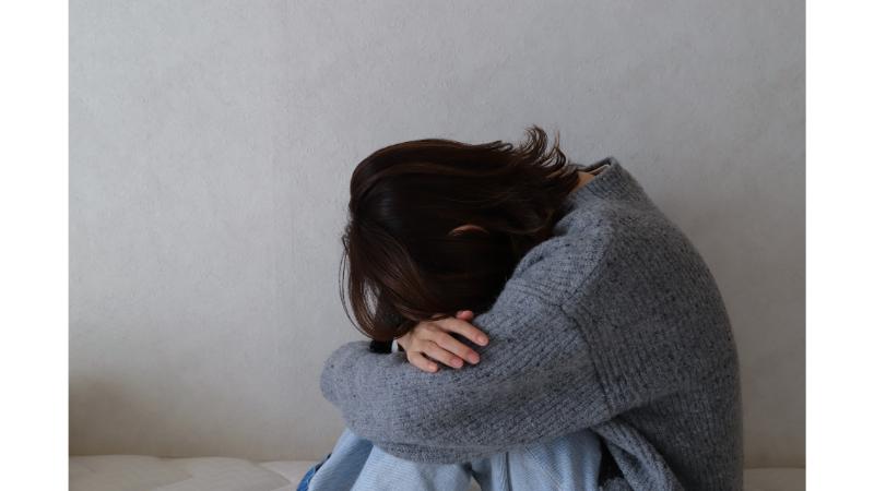 体育座りでふさぎ込む女性のモノクロ写真